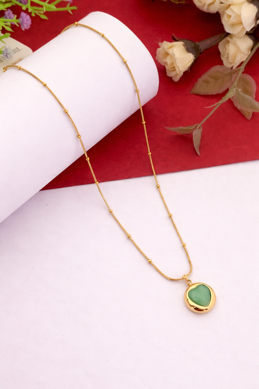 Sivorae steel gold heart pendant necklace with green stone for women displayed on elegant red and white background.