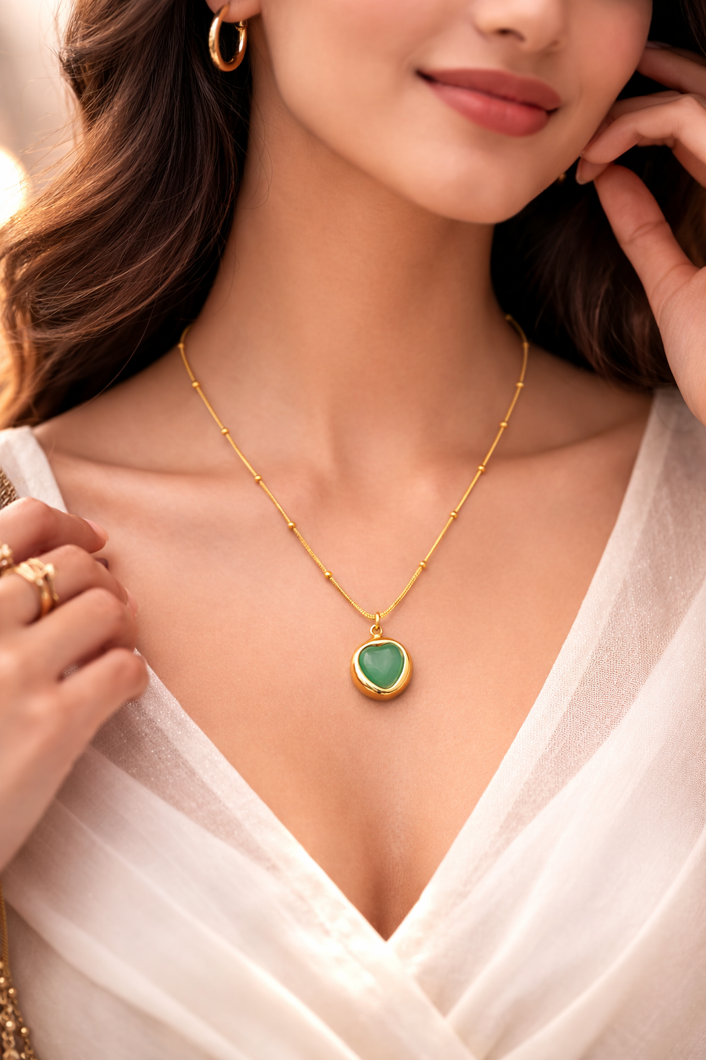 Woman wearing Sivorae gold heart pendant necklace with green stone, elegant lifestyle jewelry look.